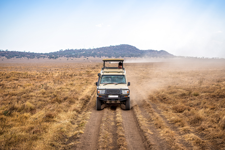 Safari vehicle driving through dry landscape